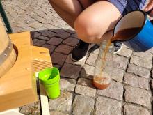 Hier kommt Apfelsaft aus dem Ausguss der Apfelsaftpresse.