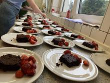 Viele Teller mit dem Nachtisch: Schwarze-Bohnen-Brownie und Erdbeeren.